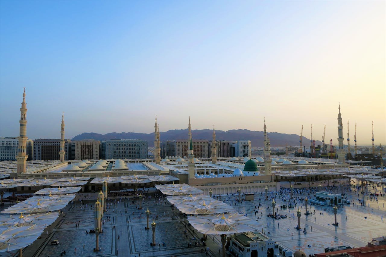 Aerial view of Al-Masjid an-Nabawi with minarets at sunset in Medina, Saudi Arabia.